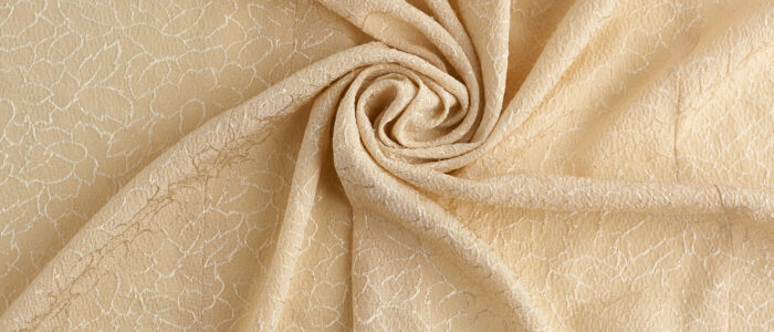 beige satin textile fabric with embroidery elements, piece of ca